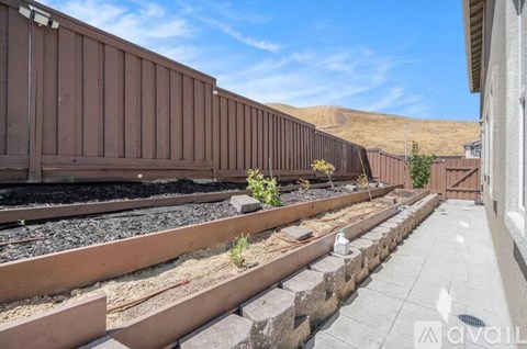 A train track with a brown train car on the left and a building on the right.