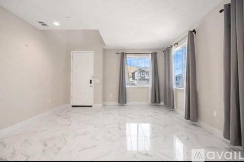 A spacious room with marble flooring and a view of the outside through the windows.
