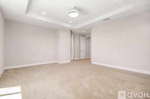 A spacious room with beige carpeting and white walls.