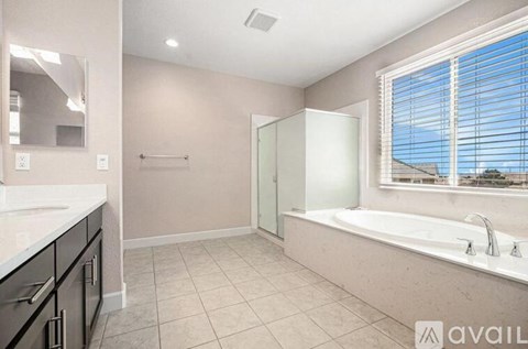 A bathroom with a tub, sink, and mirror.