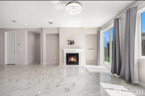 A spacious living room with a fireplace and grey curtains.