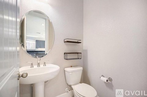 A bathroom with a toilet, sink, mirror, and towel rack.