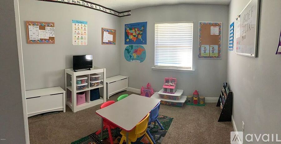 A classroom with a whiteboard, posters, and a table with colorful chairs.