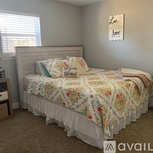 A bed with a floral bedspread and pillows that say "Beyond Blessed".