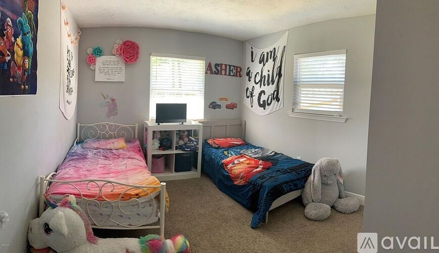 A child's bedroom with two beds, a desk, and a teddy bear.