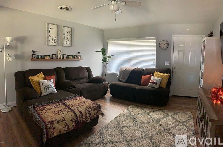 A living room with a brown couch and a rug.