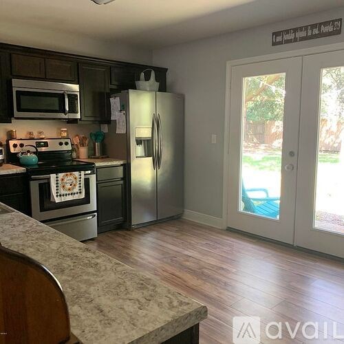 A kitchen with a refrigerator, microwave, and oven.
