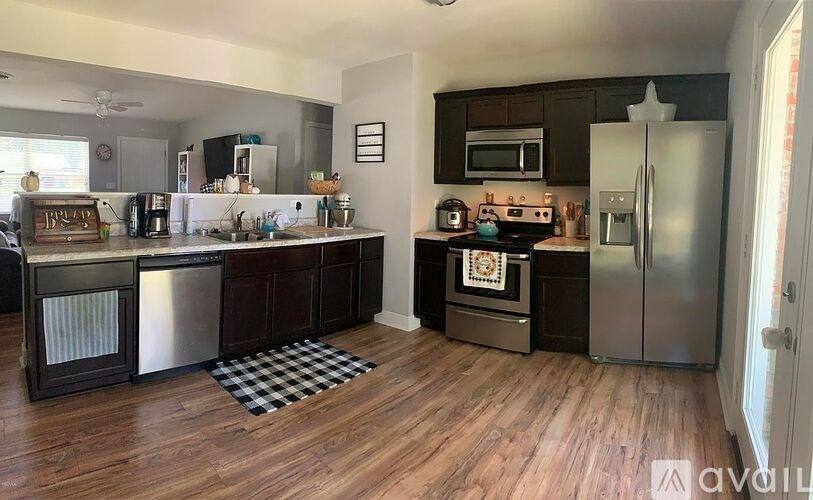 A kitchen with wooden floors and a checkered mat on the floor.