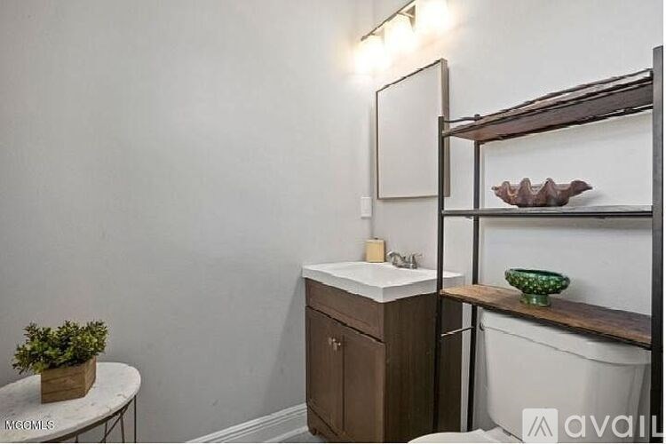 A bathroom with a sink, mirror, and shelf.