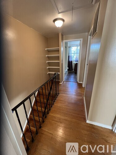 A hallway with a staircase and a railing.