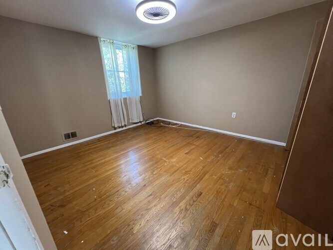 A room with wooden flooring and a window with curtains.