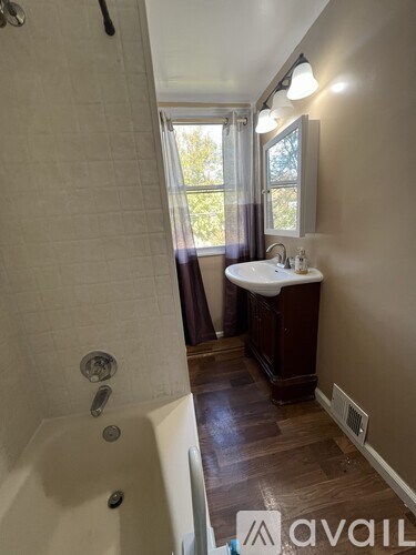 A bathroom with a tub, sink, and window.