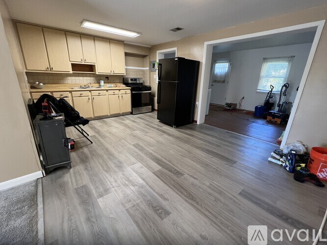 A kitchen with a black fridge and wooden floors.