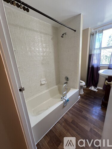 A bathroom with a white tub and wooden floors.