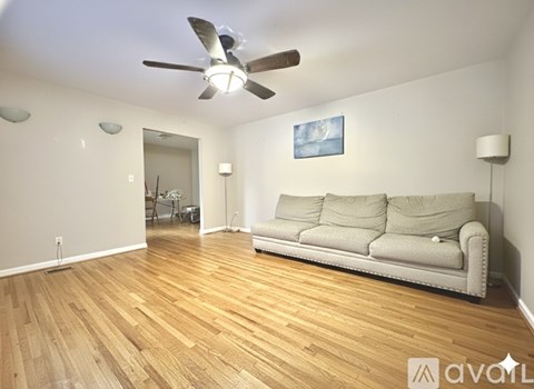 A living room with a couch, a ceiling fan, and a painting on the wall.