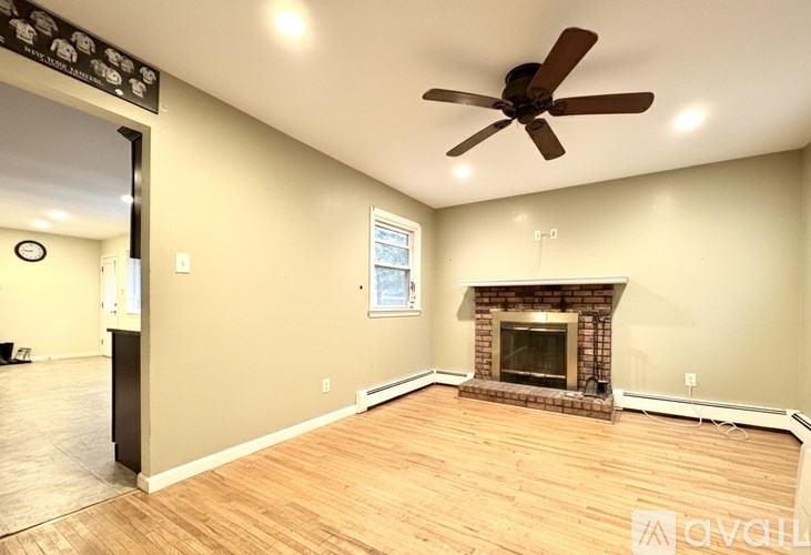 A living room with a fireplace and a ceiling fan.