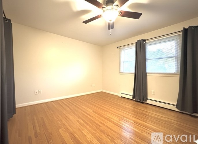 A room with a ceiling fan and wooden flooring.