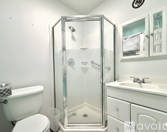 A white bathroom with a glass shower stall and a toilet.