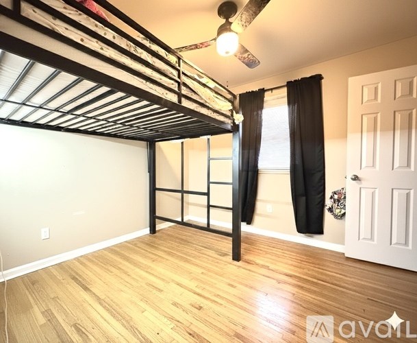 A room with a bunk bed and a window with black curtains.