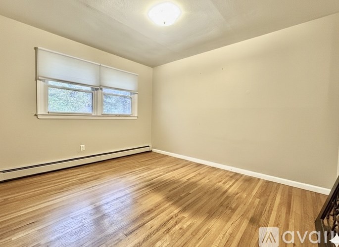 A room with wooden flooring and a window with blinds.