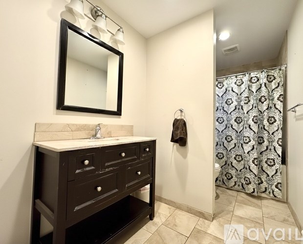 A bathroom with a sink, mirror, and shower.