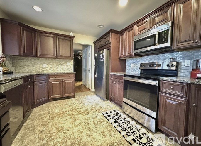 A kitchen with brown cabinets and a rug on the floor.