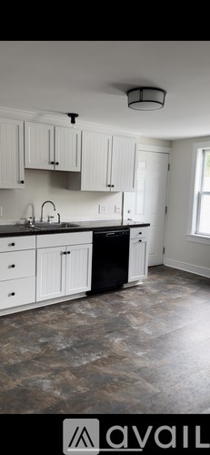 A kitchen with white cabinets and a black dishwasher.