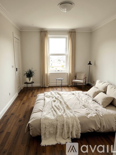 A bedroom with a large bed and a window with curtains.