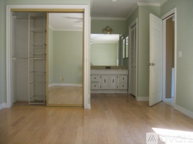 A room with a wooden floor and a large mirror on the wall.