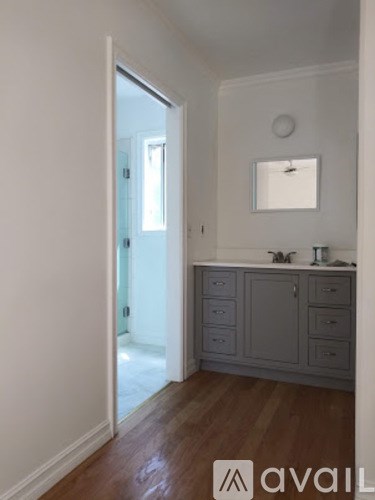 A bathroom with a wooden floor and a white wall.