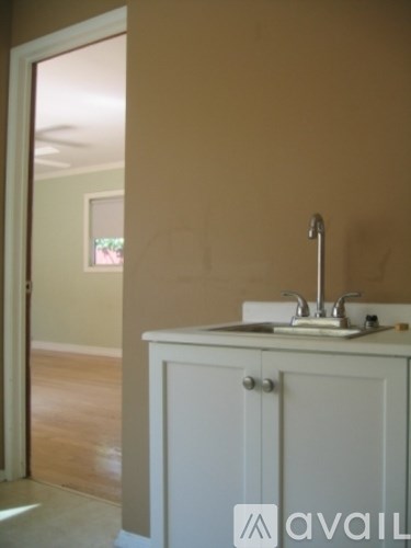 A white sink is on a white cabinet in a room with beige walls.