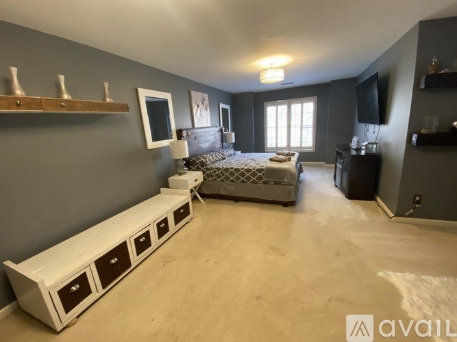 A bedroom with a bed, dresser, and a window with sunlight coming through.