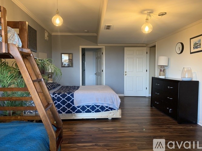 A bedroom with a bed, dresser, and a plant.