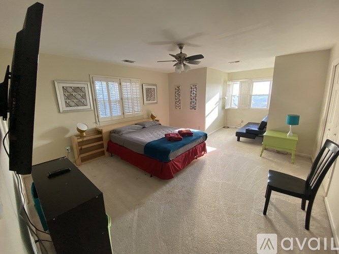 A bedroom with a bed, chair, and ceiling fan.