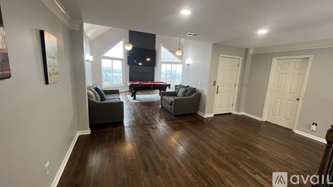 A living room with a pool table and two couches.