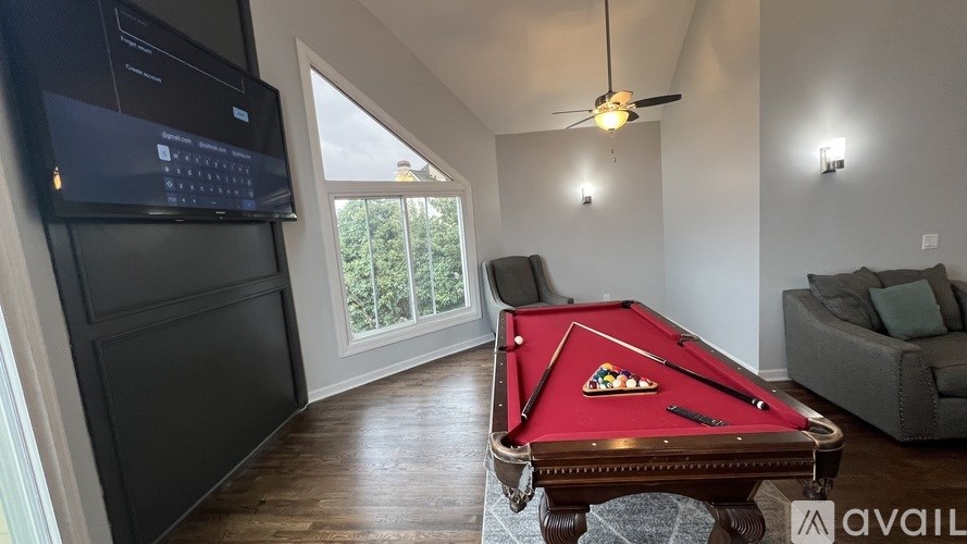 A pool table with a pizza slice on it is in the middle of a room with a television and a couch.