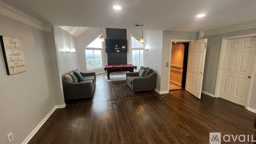 A living room with a couch, a chair, and a sign on the wall.