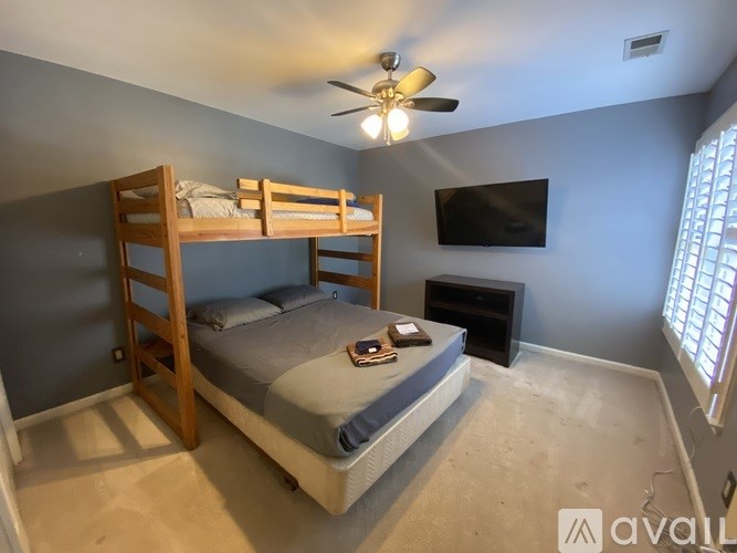 A bedroom with a bunk bed and a flat screen TV mounted on the wall.