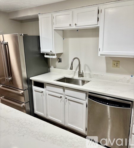 A kitchen with white cabinets and a stainless steel dishwasher.