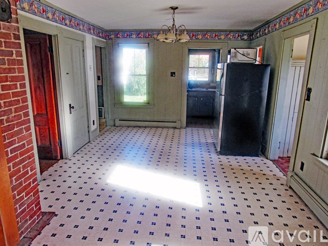 A room with a black fridge and a tiled floor.
