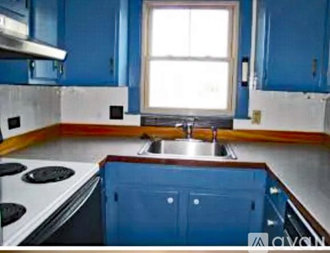 A kitchen with blue cabinets and a white stove top.