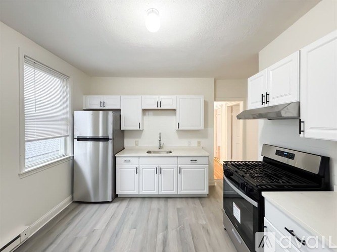 A kitchen with white cabinets and a stainless steel refrigerator.