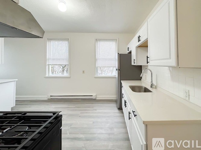 A kitchen with a black stove top oven and white cabinets.