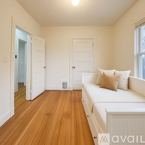 A living room with a white couch and wooden floors.