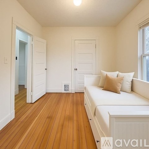 A living room with a white couch and wooden floors.
