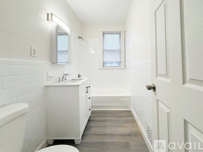 A white bathroom with a tub, sink, and mirror.