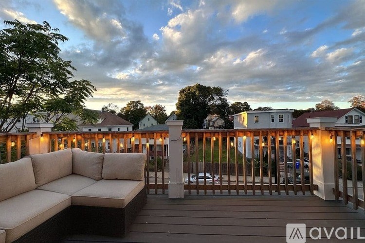 A balcony with a couch and lights under a cloudy sky.