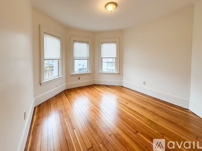 A room with wooden floors and two windows.