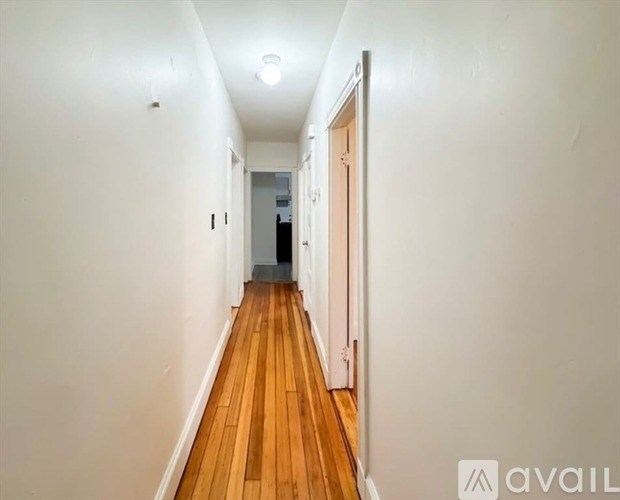 A long hallway with wooden floors and white walls.