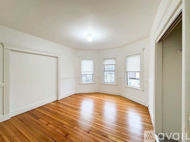 A room with wooden floors and three windows.